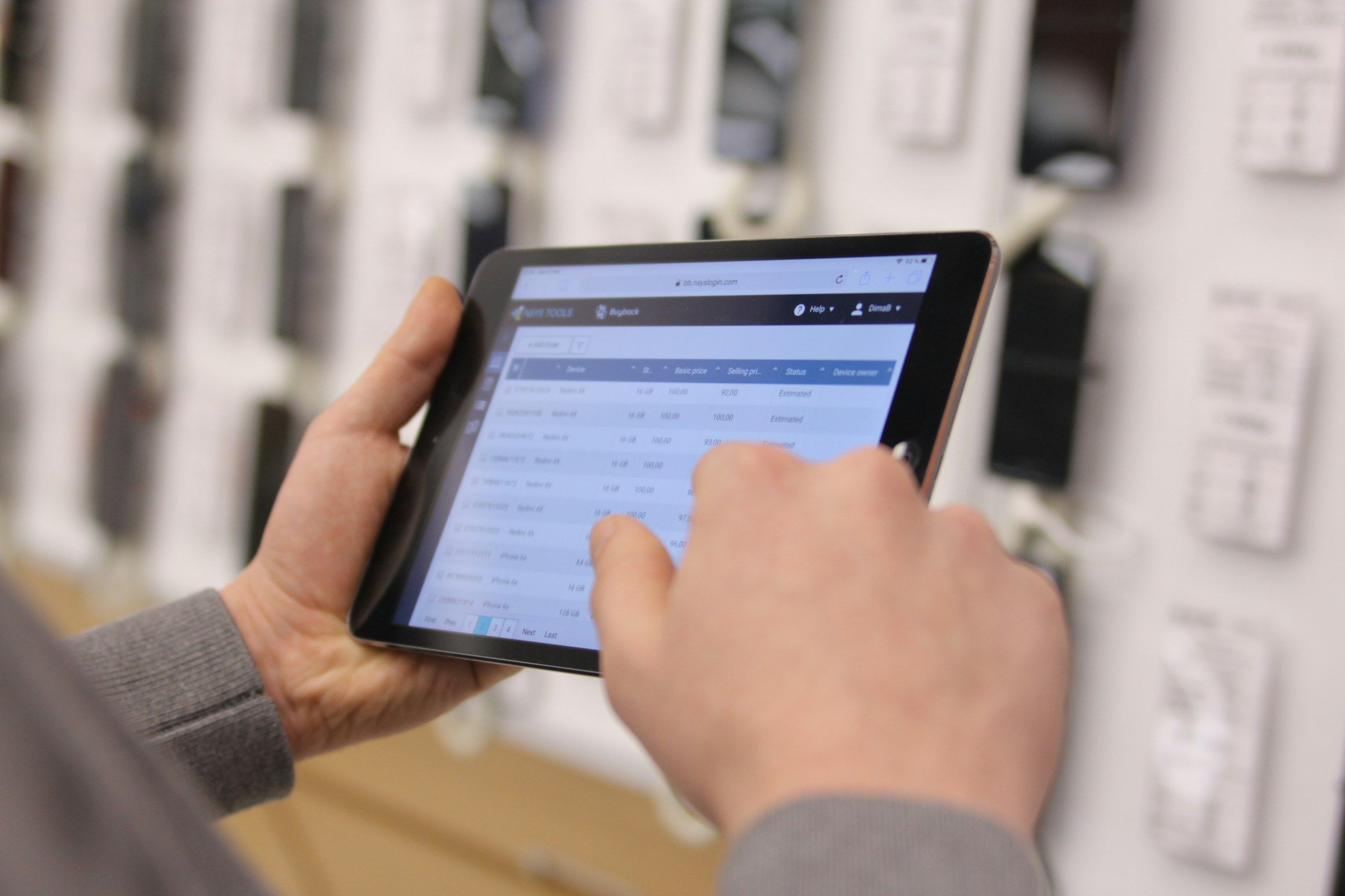 Hände halten ein Tablet mit einer Liste, im Hintergrund ein Regal